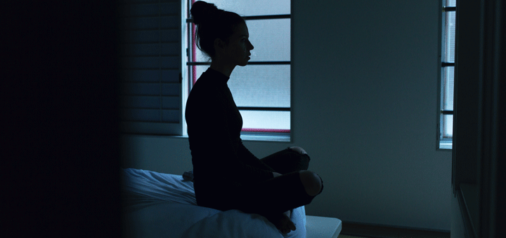 Frau sitzt wegen Depressionen alleine im Zimmer im Dunkeln