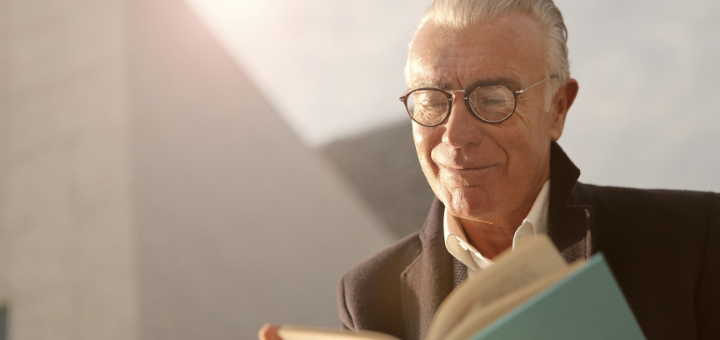 Mann mit Alterssichtigkeit liest ein Buch dank Lesebrille